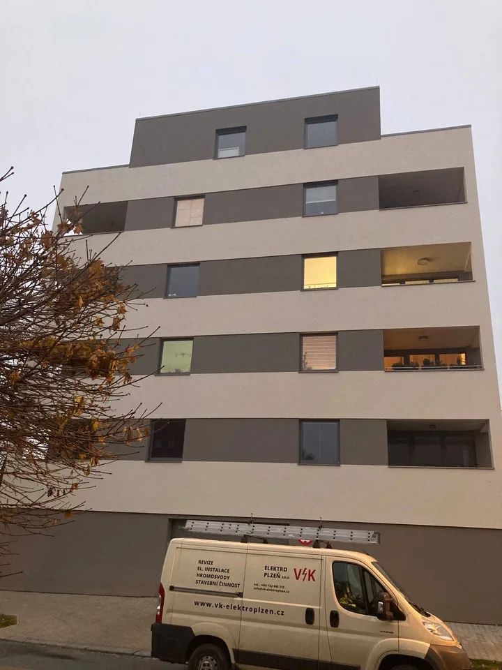 Bytový dům v Plzni s montážním vozem VK Elektro Plzeň před vchodem
